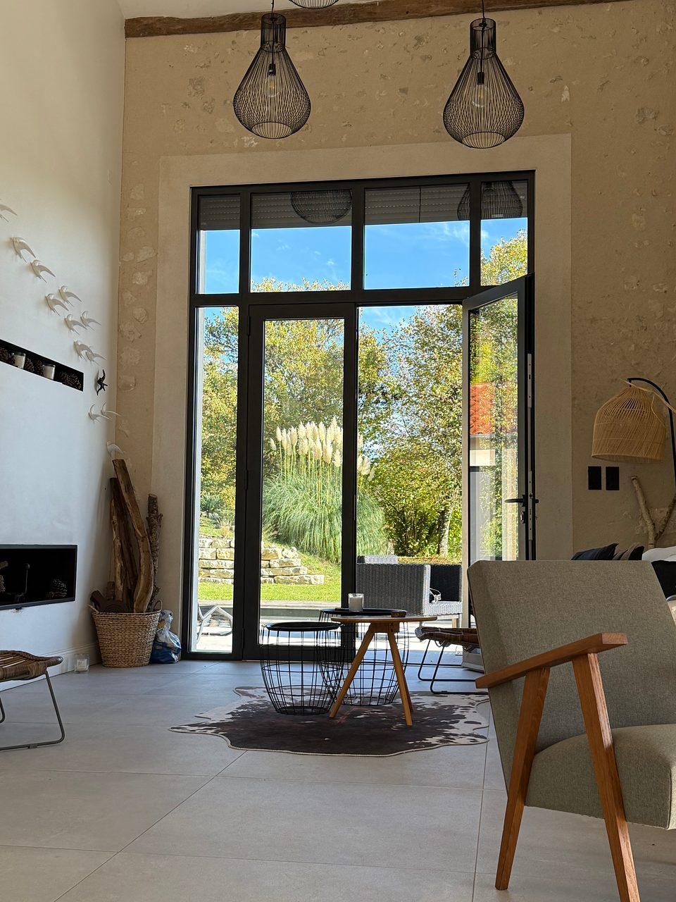 Der Wohnraum mit hoher Decke und großer Glasfront zum Garten
