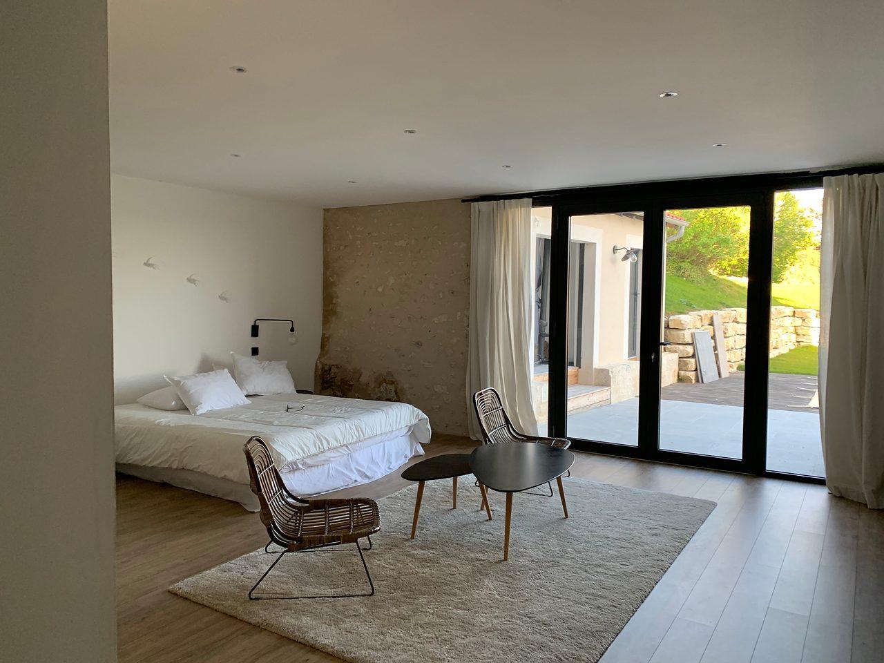 Die 60 m² große Master-Suite: Doppelbett, Sitzecke, Natursteinwand und Glastür zum Garten