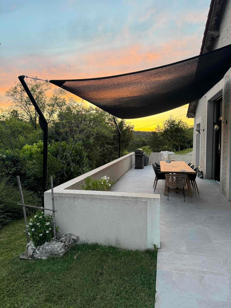 The terrace and its shade sail at sunset, facing the valley